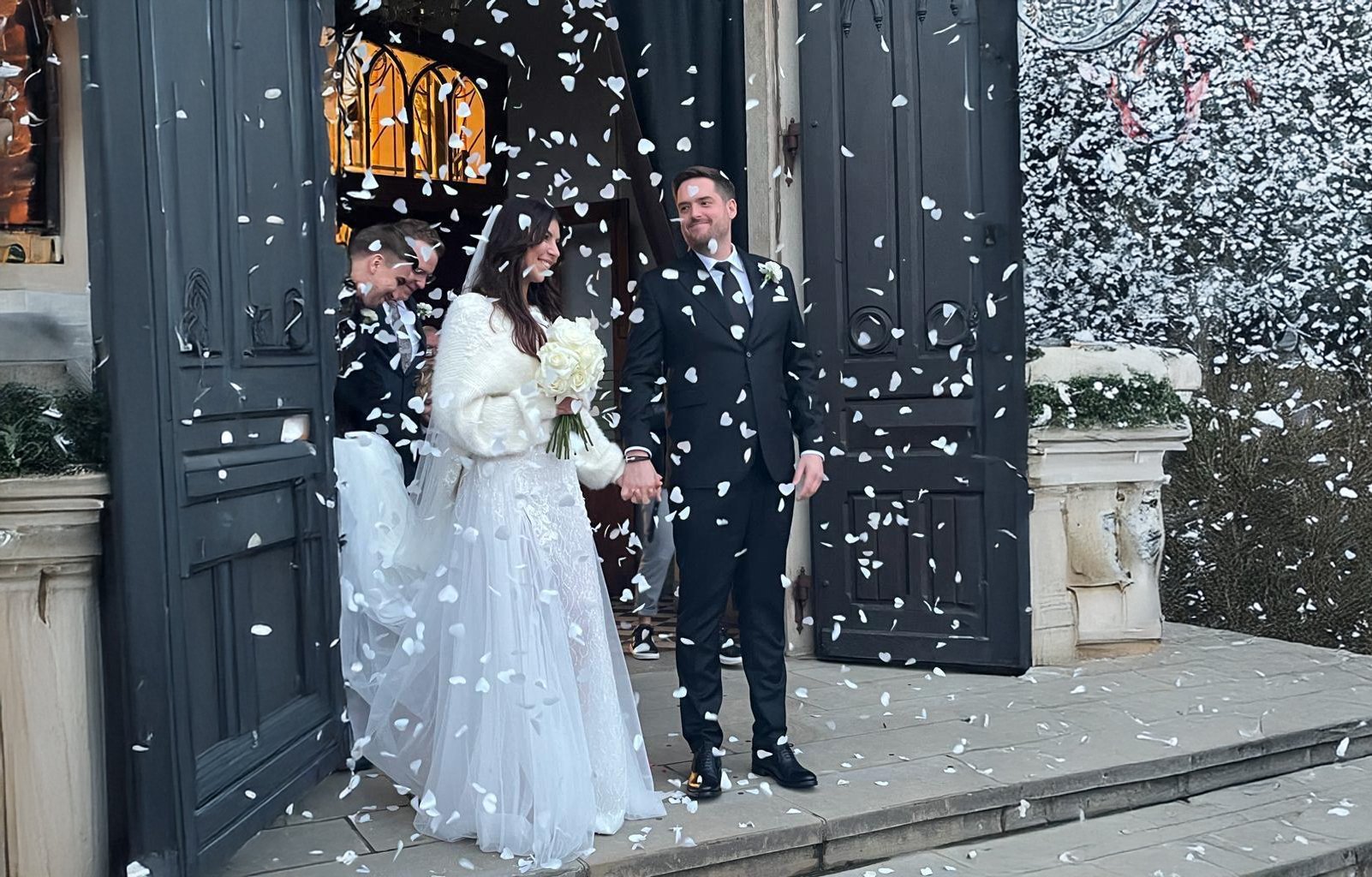 Bride and groom exit church doorway while petals are thrown during wedding ceremony