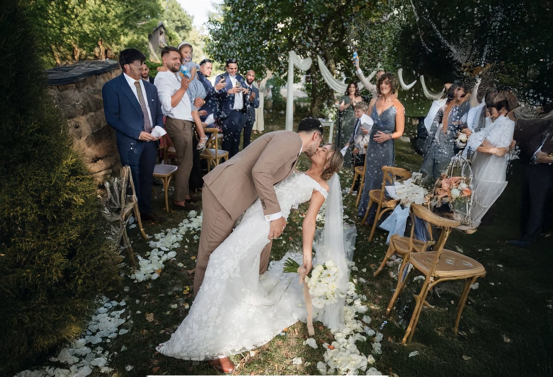 Bride and groom exchanging vows during outdoor garden wedding ceremony surrounded by guests